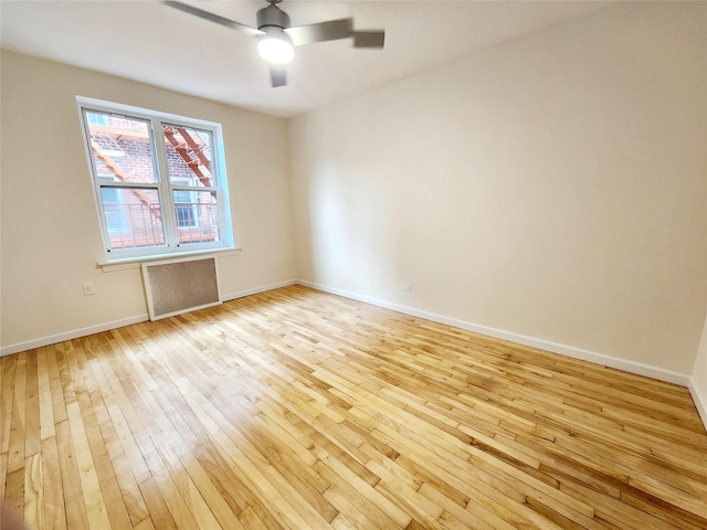 spare room featuring radiator, light hardwood / wood-style flooring, and ceiling fan