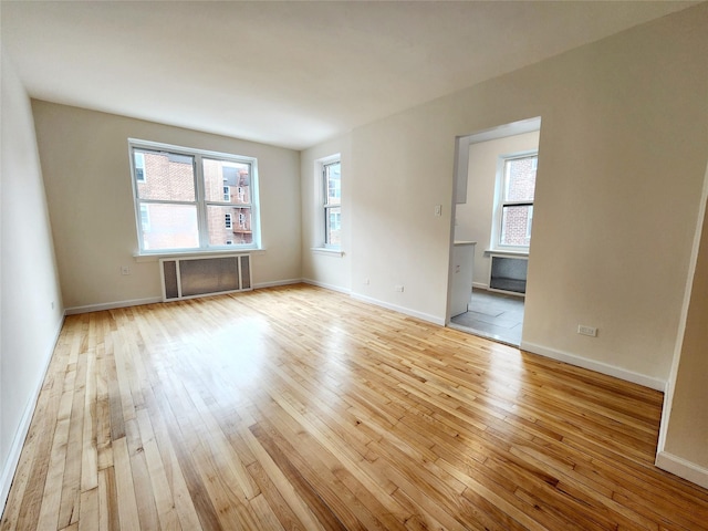 empty room featuring radiator heating unit and light hardwood / wood-style floors