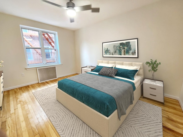 bedroom featuring radiator, ceiling fan, and light hardwood / wood-style flooring