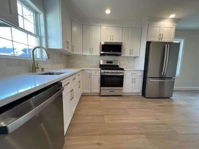 kitchen featuring sink, stainless steel appliances, white cabinets, and decorative backsplash