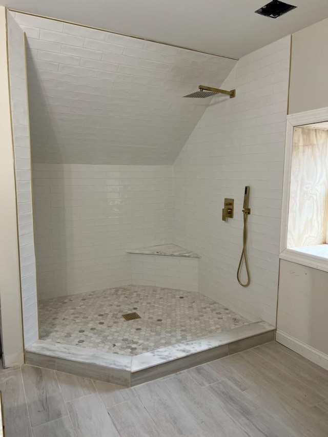 bathroom featuring vaulted ceiling and a tile shower