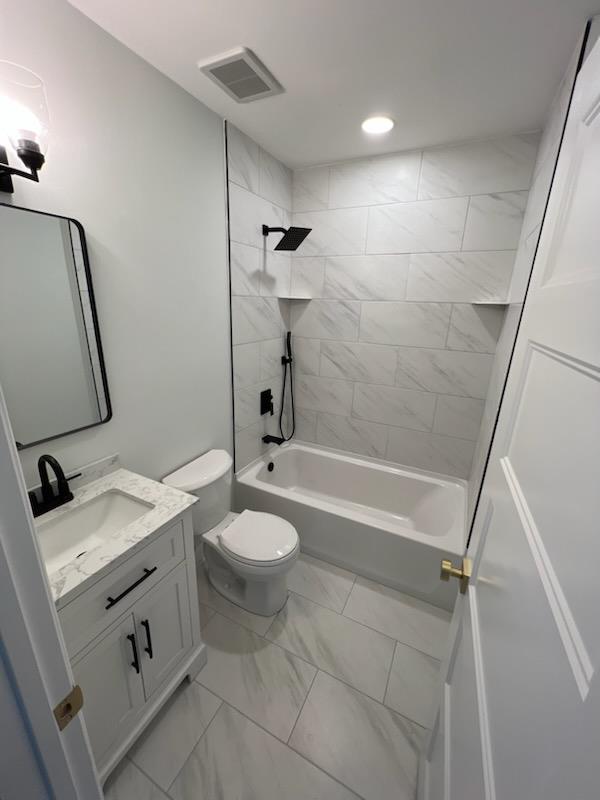 full bathroom with toilet, vanity, and tiled shower / bath