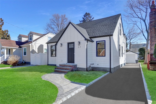 view of front of home featuring a garage, a shingled roof, an outbuilding, board and batten siding, and a front yard