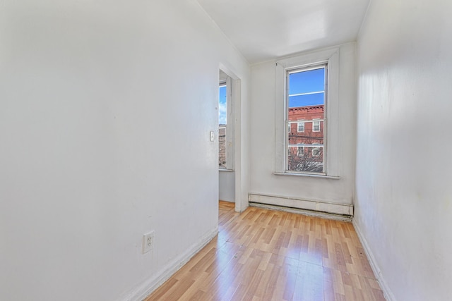 empty room with light wood-type flooring and baseboard heating