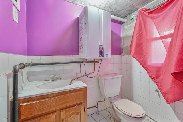 bathroom featuring vanity, tile patterned floors, tankless water heater, toilet, and tile walls