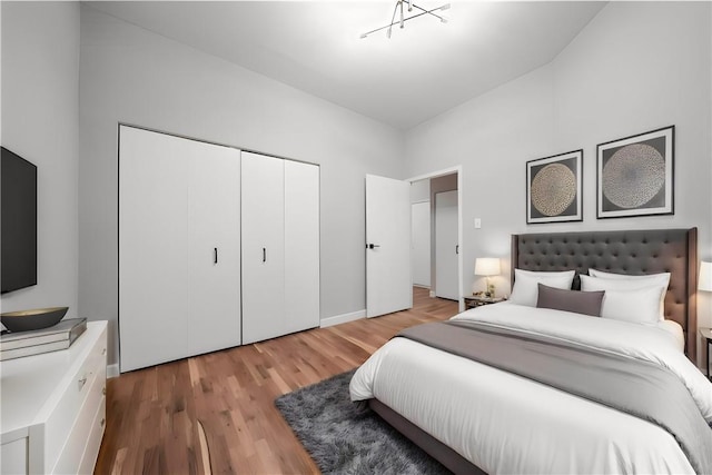 bedroom with light hardwood / wood-style flooring, a closet, and lofted ceiling