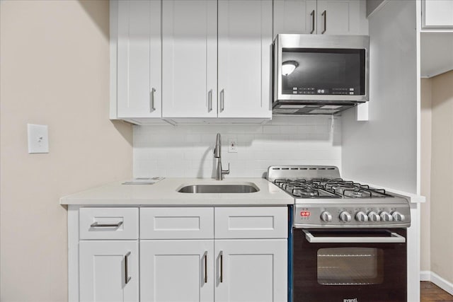 kitchen with white cabinets, stainless steel appliances, tasteful backsplash, and sink