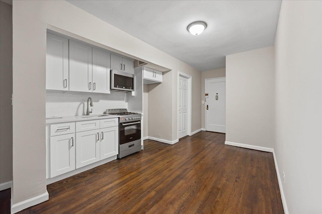 kitchen featuring sink, tasteful backsplash, dark hardwood / wood-style floors, white cabinets, and appliances with stainless steel finishes