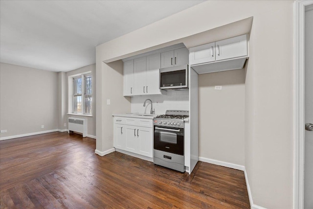 kitchen featuring dark hardwood / wood-style flooring, stainless steel appliances, sink, white cabinets, and radiator heating unit