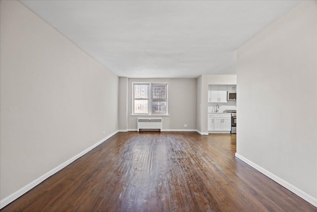 unfurnished living room with radiator heating unit and dark wood-type flooring