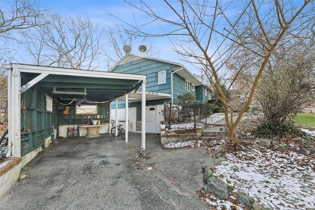 snow covered parking featuring a carport