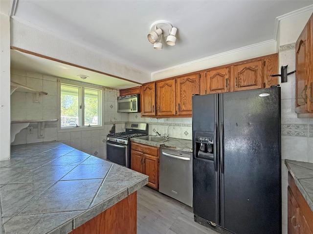 33 Birch Ct, Riverhead, NY 11901 - kitchen featuring stainless steel appliances, brown cabinets, ornamental molding, a sink, and decorative backsplash