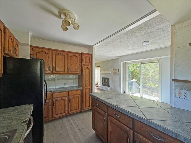 33 Birch Ct, Riverhead, NY 11901 - kitchen featuring freestanding refrigerator, brown cabinets, light wood-style flooring, and a fireplace