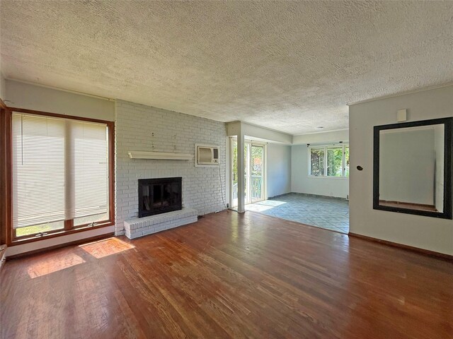 33 Birch Ct, Riverhead, NY 11901 - unfurnished living room with a textured ceiling, wood finished floors, a fireplace, an AC wall unit, and baseboards