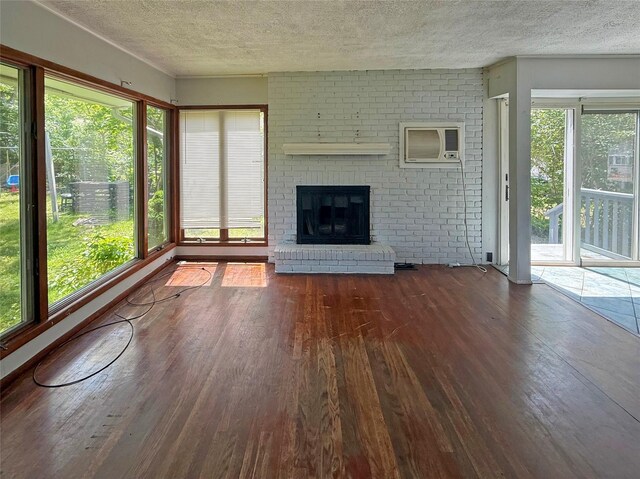 33 Birch Ct, Riverhead, NY 11901 - unfurnished living room featuring hardwood / wood-style floors, a textured ceiling, a wall mounted air conditioner, and a fireplace
