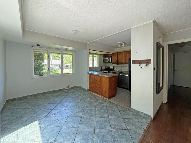 33 Birch Ct, Riverhead, NY 11901 - kitchen featuring appliances with stainless steel finishes, brown cabinetry, a textured ceiling, a peninsula, and baseboards