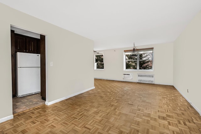 unfurnished living room with a wall mounted air conditioner, radiator heating unit, and light parquet floors