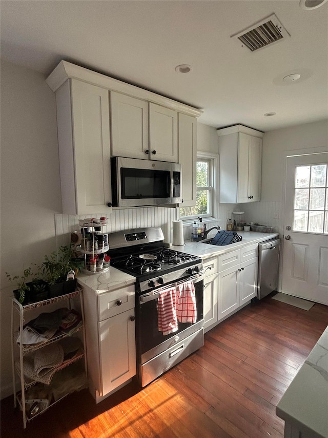 kitchen with white cabinets, plenty of natural light, stainless steel appliances, and dark wood-type flooring