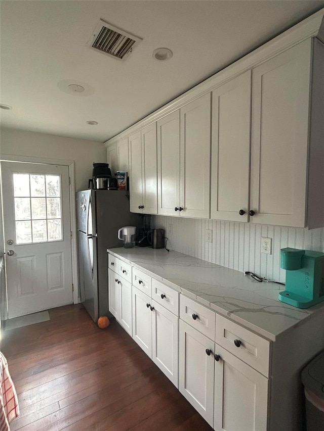 kitchen featuring tasteful backsplash, light stone counters, white cabinets, and dark wood-type flooring