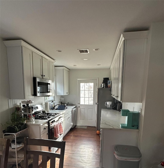 kitchen featuring light stone countertops, appliances with stainless steel finishes, dark wood-type flooring, sink, and white cabinets