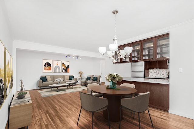 dining room with crown molding, light wood-style flooring, and an inviting chandelier