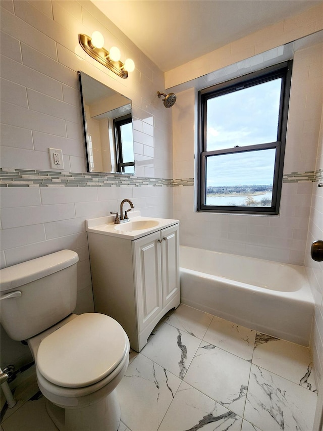 full bathroom with tiled shower / bath, vanity, toilet, and tile walls