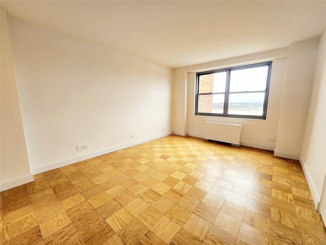 unfurnished room featuring radiator and light parquet floors