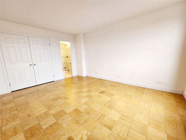 unfurnished bedroom featuring ensuite bath and light parquet floors