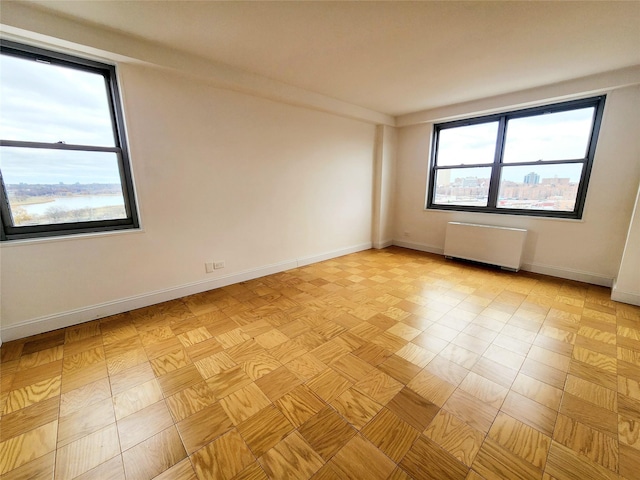 empty room with a water view, radiator, and light parquet floors