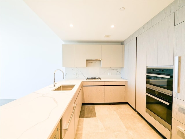 kitchen with light stone countertops, tasteful backsplash, white gas stovetop, sink, and light brown cabinets