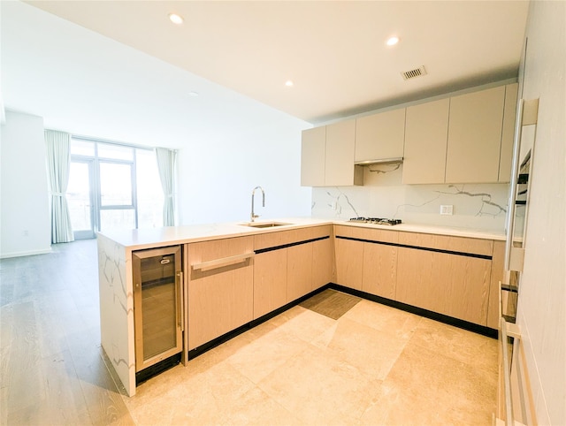 kitchen featuring visible vents, white gas cooktop, a sink, beverage cooler, and a peninsula