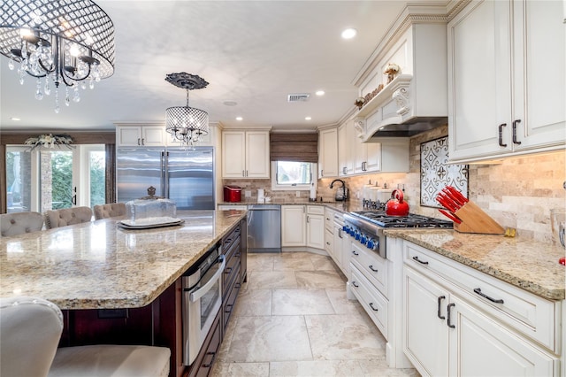 kitchen featuring a kitchen breakfast bar, backsplash, stainless steel appliances, pendant lighting, and an inviting chandelier