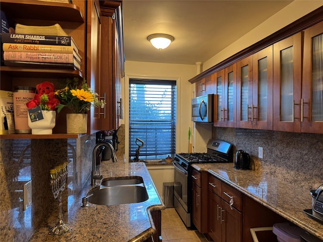 kitchen with sink, stainless steel appliances, backsplash, dark stone counters, and light tile patterned floors