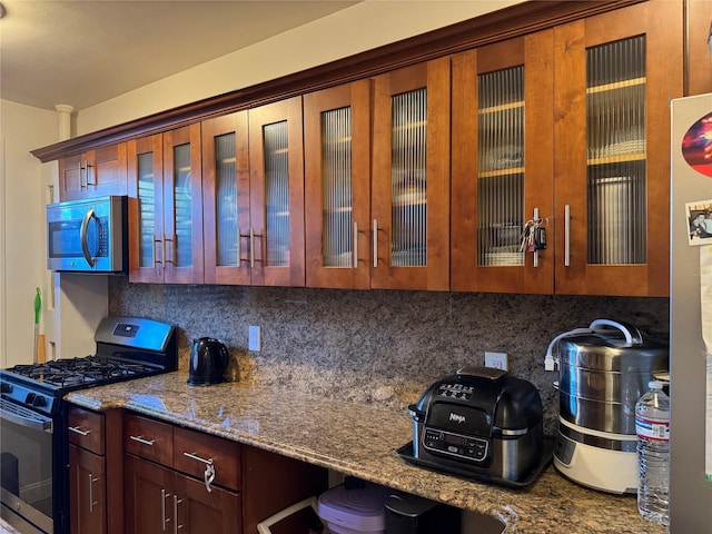 kitchen featuring backsplash, appliances with stainless steel finishes, and dark stone counters