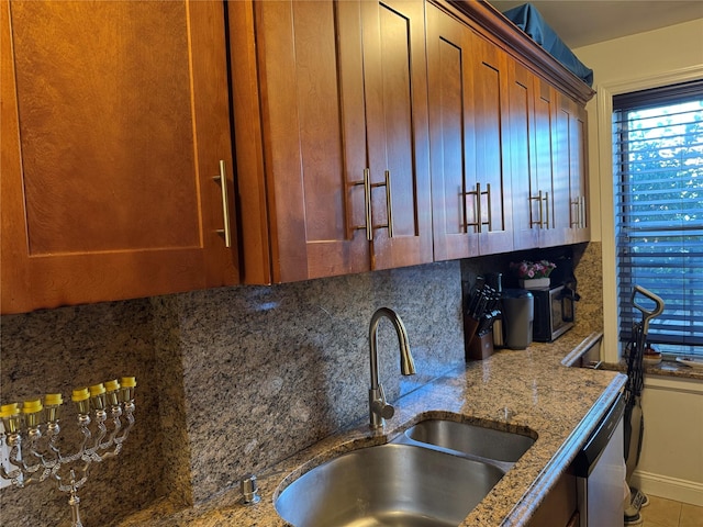 kitchen featuring dishwasher, tile patterned floors, sink, decorative backsplash, and light stone countertops