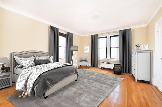 bedroom featuring crown molding, radiator heating unit, and light hardwood / wood-style flooring