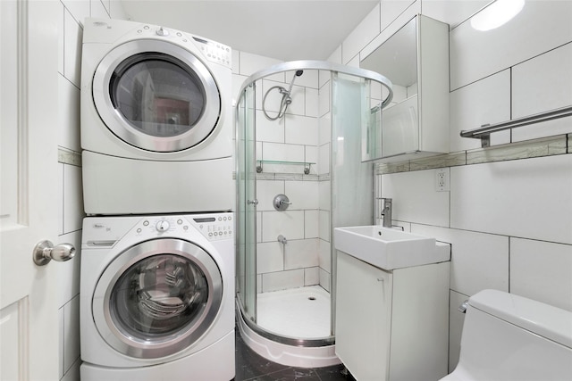 washroom featuring stacked washer / drying machine, sink, and tile walls