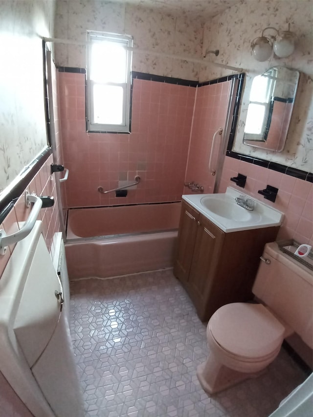 full bathroom with toilet, vanity, tile walls, and tiled shower / bath