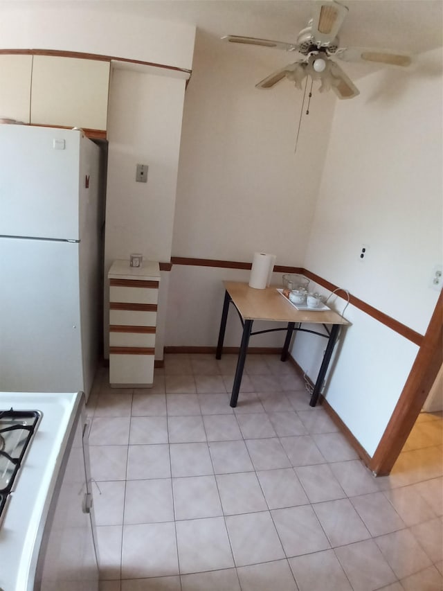 kitchen featuring stove, white cabinets, white refrigerator, ceiling fan, and light tile patterned floors