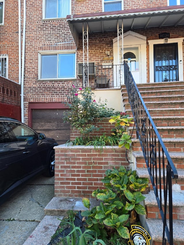 entrance to property featuring an attached garage and brick siding