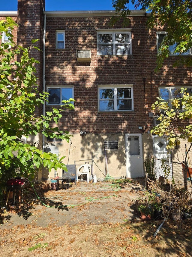 back of house featuring fence and brick siding