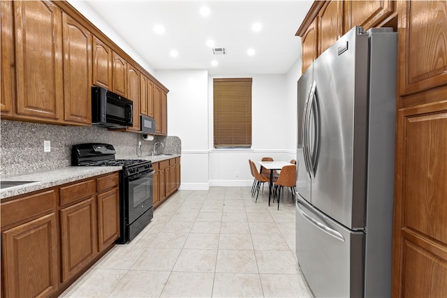 kitchen with sink, light stone counters, decorative backsplash, light tile patterned flooring, and black appliances