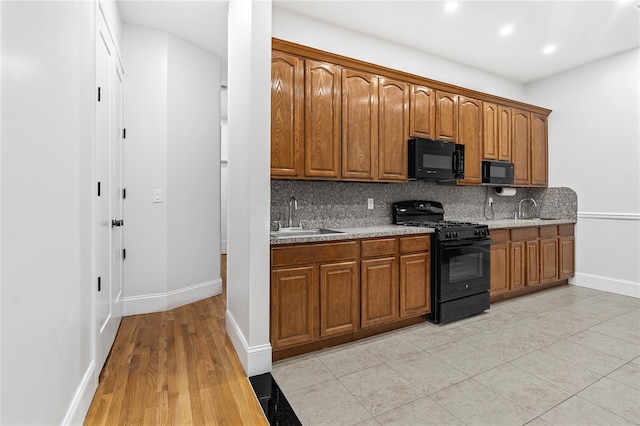 kitchen with backsplash, sink, light tile patterned floors, and black appliances