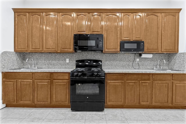 kitchen featuring backsplash, sink, light tile patterned floors, and black appliances