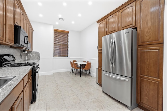 kitchen featuring black appliances, light tile patterned floors, and backsplash