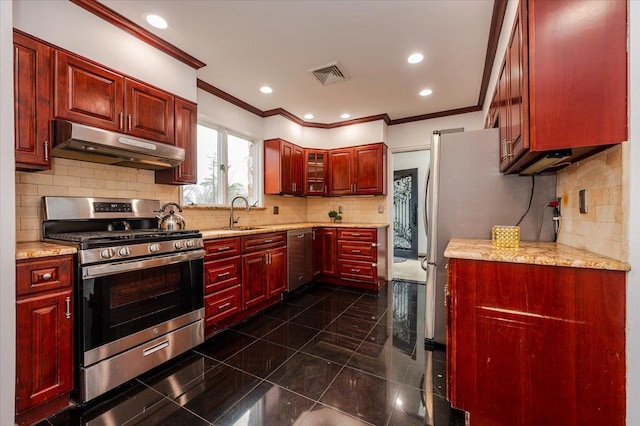 kitchen with appliances with stainless steel finishes, backsplash, light stone counters, and sink