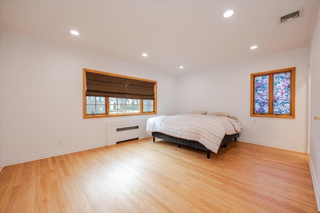 bedroom with radiator, crown molding, and light hardwood / wood-style floors