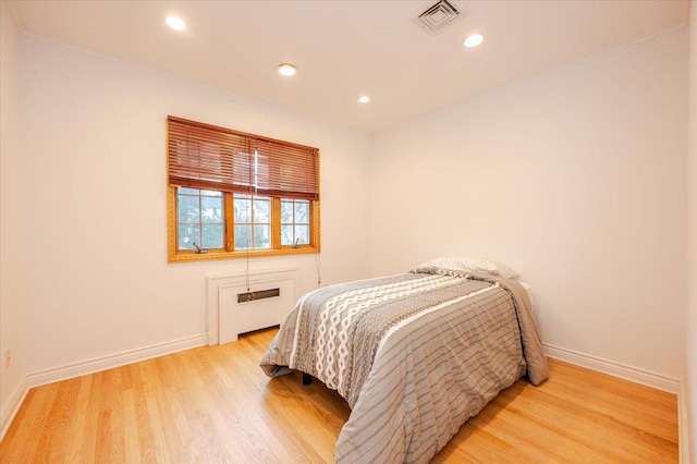 bedroom with light hardwood / wood-style flooring and radiator