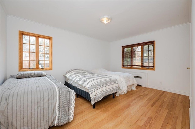 bedroom with radiator heating unit, light hardwood / wood-style flooring, and ornamental molding