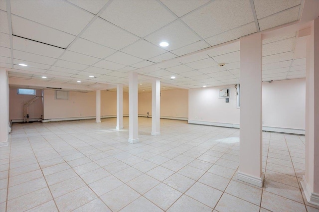 basement with a paneled ceiling and a baseboard heating unit